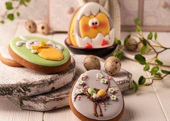 Fototapeta na wymiar easter cookies with painted easter bunny, easter eggs and chicken near decorative buffet and napkin on white cutting boards and wooden background