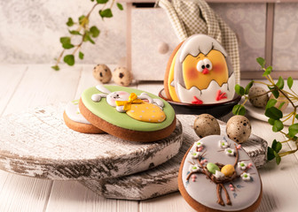 easter green cookies with painted easter bunny, easter eggs and hatched chicken near quail eggs, decorative buffet and napkin on wooden cutting boards
