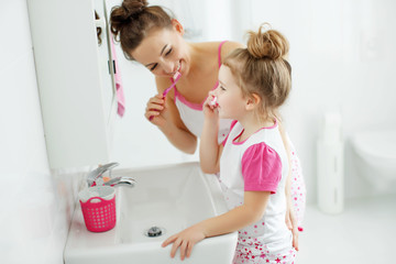 Woman and child brush their teeth 