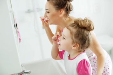 Woman and child brush their teeth 