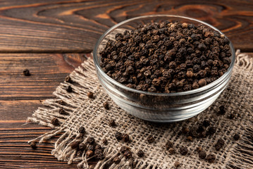 Black pepper on dark wooden background. 