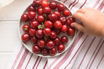 cherry bowl and kids hand, top view