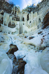 Fototapeta na wymiar Beautiful frozen waterfall with frozen trees in Vallaste, Estonia.