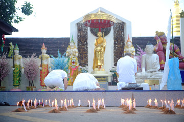 Night in the light of candles in the morning. The people on background pray the buddha in Thailand.
