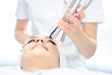 Cosmetology. Laser device. The cosmetologist performs a facial rejuvenation procedure.