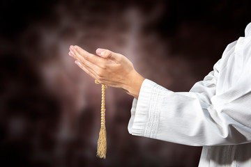 Muslim man praying with prayer beads on his hands