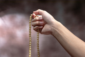 Muslim hands praying with prayer beads
