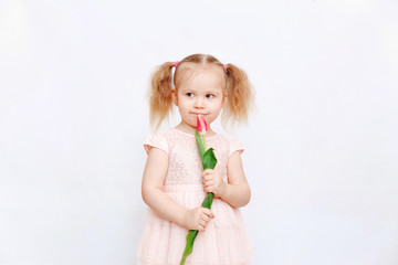 Little beautiful girl blonde with a bouquet of tulips on a light background. Baby girl smiling. Spring and women's day concept. Little girl holding a bouquet of colored tulips. Сopy spase