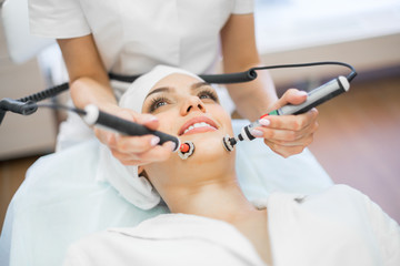 A cosmetologist performs a microcurrent therapy procedure. Cosmetology clinic.