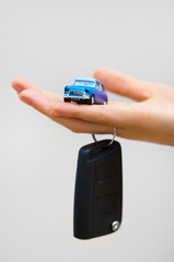 Hand holding small car toy and keys. Car purchase concept.