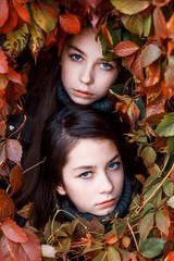 Twins sisters outside in autumn in ive leaves. unity with nature