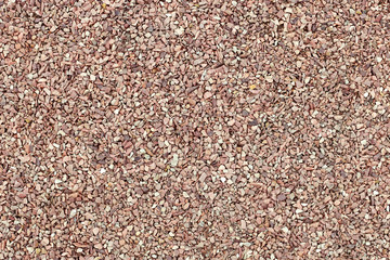 Red crushed stone, uniform coating. Industrial background.