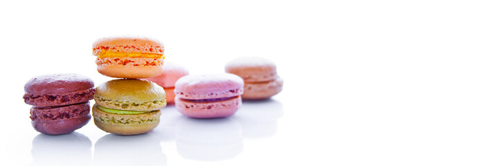 Pile of pastel colored french macarons, on white panoramic background