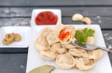 dumpling with ketchup on a fork ,a plate of boiled dumplings