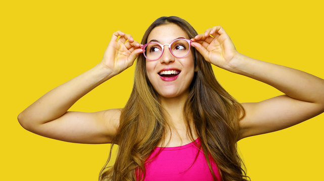 Funny portrait of excited girl wearing glasses eyewear. Closeup portrait of young woman making funny face expression isolated on yellow background. Beautiful young model.