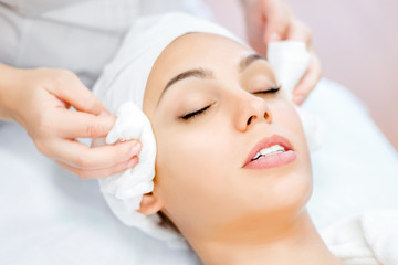 Cosmetologist hands cleanse the skin. Facial skin care. Beautiful ltdeirf on cosmetology procedure. Beauty salon visit.