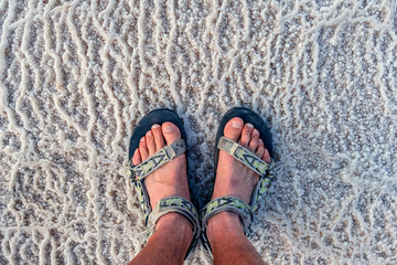 young man in the sandals stands on incredibly fantastic and unique natural patterns from the salt...