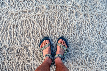 young man in the sandals stands on incredibly fantastic and unique natural patterns from the salt...
