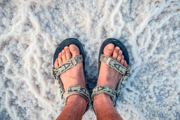 young man in the sandals stands on incredibly fantastic and unique natural patterns from the salt...