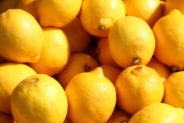 Yellow lemons in the light of the sun for sale on a marketplace