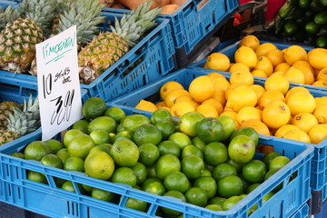 Green limes , pineapples and lemons for sale at a Dutch farmer's market, price sign with Dutch text