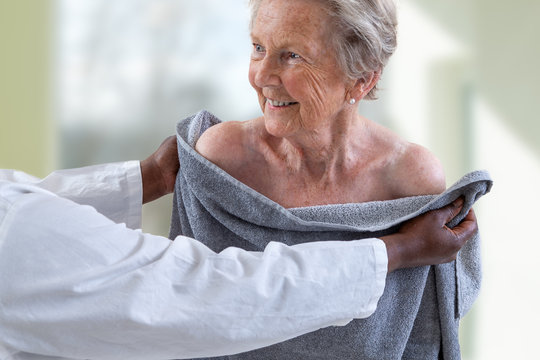 Care Giver Or Nurse Assisting Elderly Woman For Showerand Drying Her