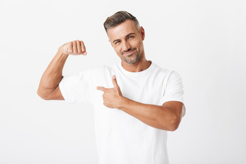 Image of happy man 30s with bristle wearing casual t-shirt showing his biceps on camera