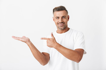 Image of attractive man 30s with bristle wearing casual t-shirt pointing finger at copyspace...