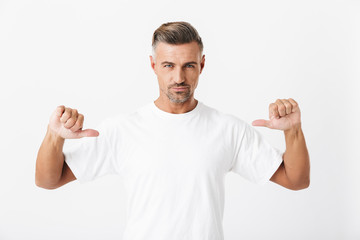 Image of confident man 30s with bristle wearing casual t-shirt pointing fingers at himself