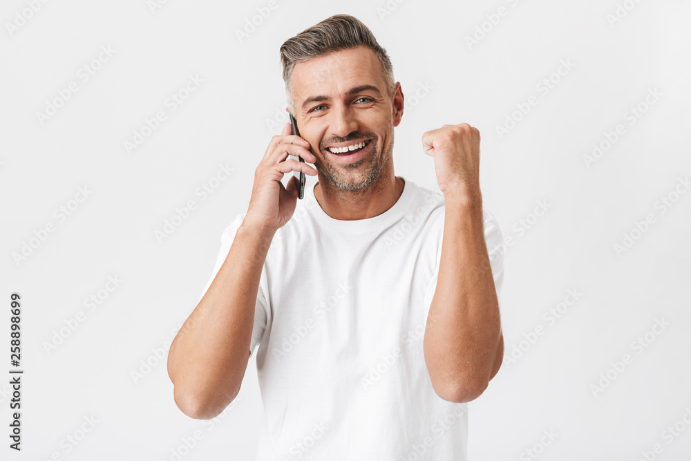 Sticker Image of happy man 30s wearing casual t-shirt holding smartphone and having mobile conversation