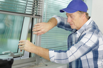 Naklejka na ściany i meble man installing a new blind on a window