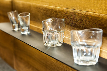 shelf with collection of decorative glasses on wooden wall background