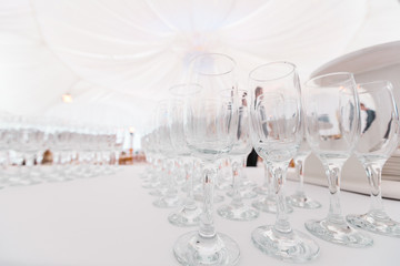 Clean glasses on white table. Catering set-up ready for the event to begin. Service area the waiter in restaurant. Banquet in the tent