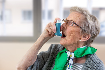 Close-up of senior woman using asthma inhaler. - obrazy, fototapety, plakaty