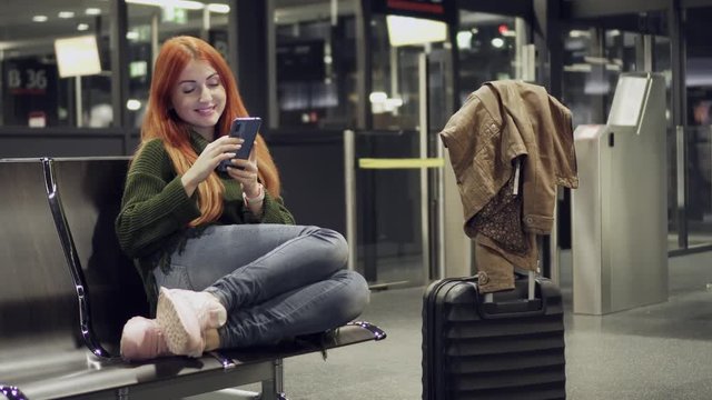 Young female uses phone in airport terminal