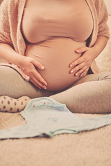 Beautiful pregnant woman touching her belly and enjoying at home.