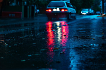 Motion car in rain with selective focus,color toned. Night road blurred, in the dark while heavy raining. Rainy night in the big city, light reflected on the road. View from the level of asphalt.