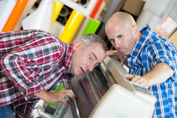 workers on offset printing machine in print factory