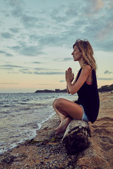 Young woman practicing yoga on the beach.