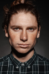 Portrait of a man with drawn hair and freckles, dressed in a checkered shirt