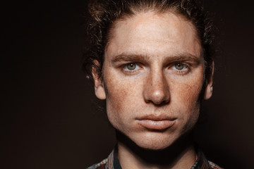 Portrait of a man with drawn hair and freckles, dressed in a checkered shirt