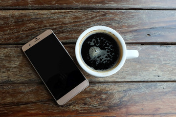 Flat lay photo of smartphone and black coffee on wood table with space for write wording, innovation that change the world such as communication way, business strategies, marketing strategies