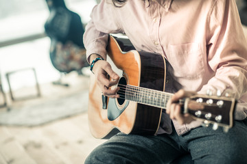 Experienced attentive musician wearing light shirt and touching strings