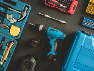 top view of Construction tools concept with Drill sets, hammer, screwdriver and Toolbox on black wooden background.