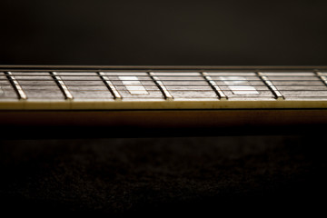 Vintage archtop guitar in natural maple close-up high angle view on black background, rosewood...