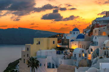 Amazing sunset view of traditional white houses in Oia village on Santorini island, Greece.