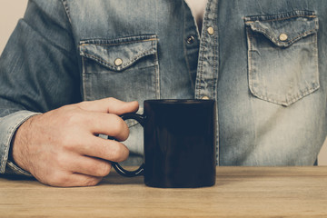 Hombre  sosteniendo una taza de café. Vista de cerca y de frente