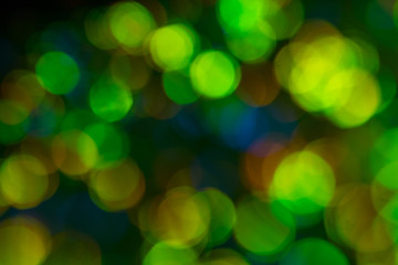Blurred golden and green bokeh circles on dark background. Defocused lens flare glow.