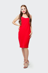 Elegant model woman wearing red dress and high heels shoes standing against white wall background