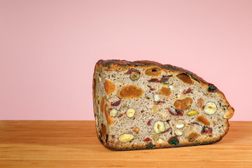 Bread with dried fruits and nuts on a cutting Board on a pink background